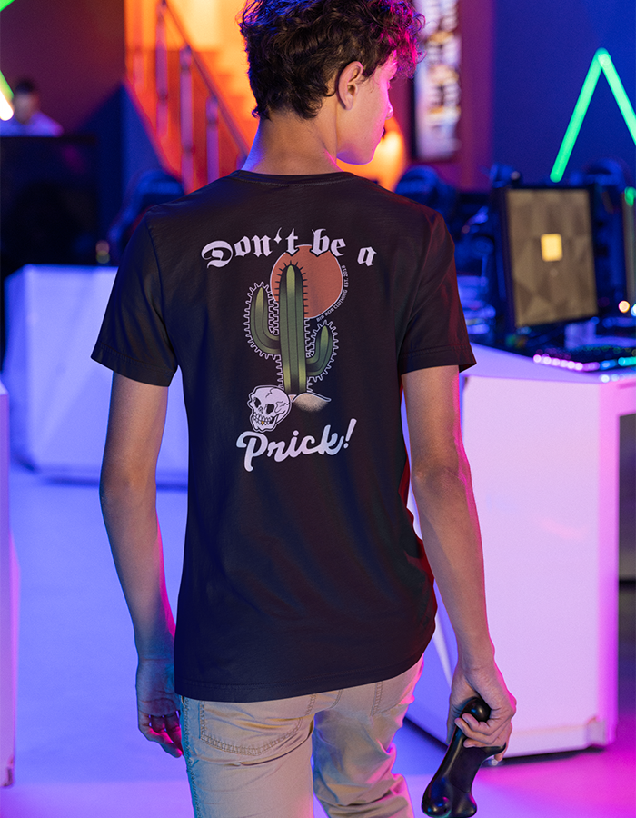 A person wearing a black t-shirt with the text 'Don't be a Prick!' printed on the back, featuring a graphic of a cactus and a skull.