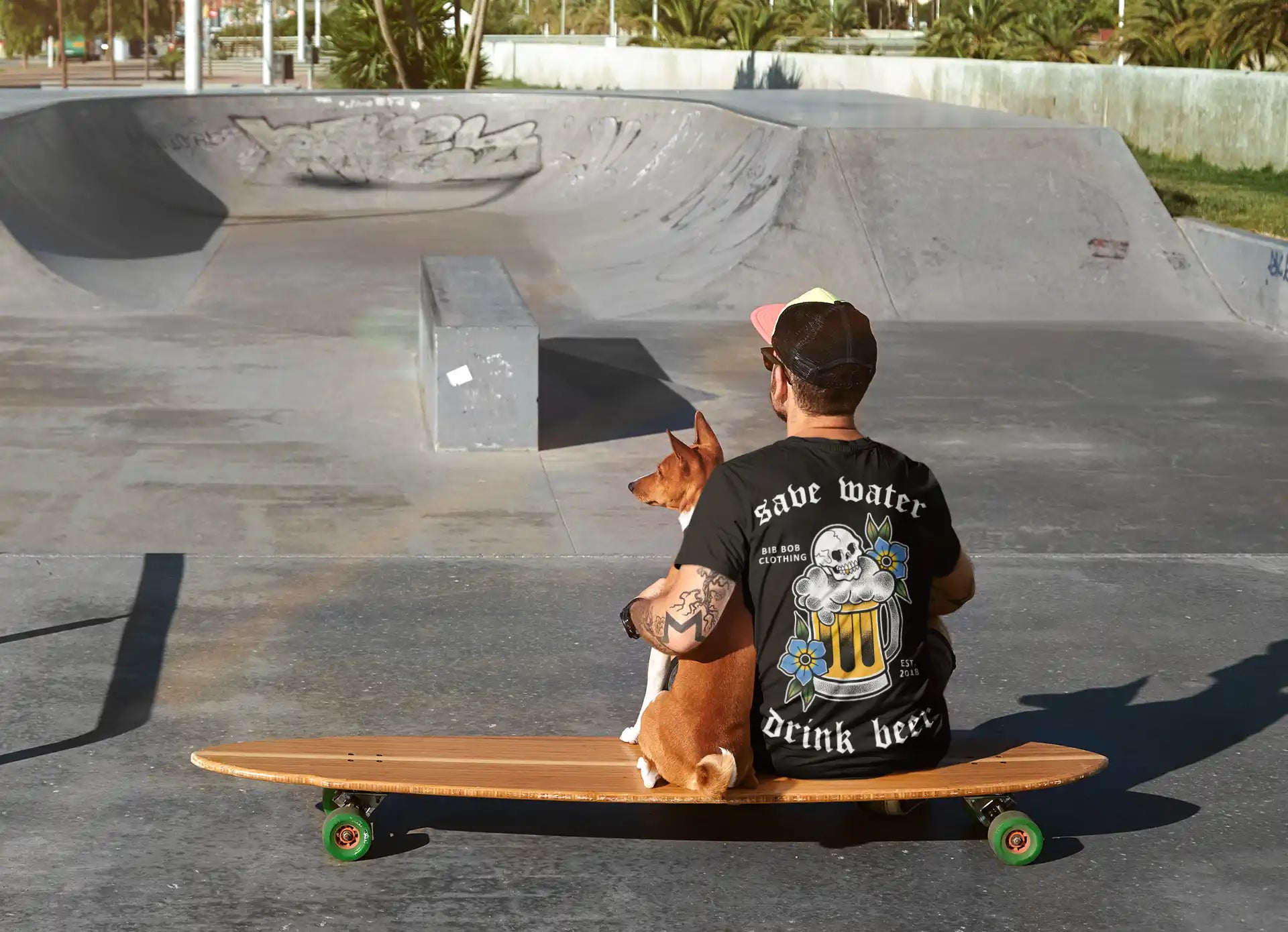 A person and a dog sitting on a longboard skateboard.